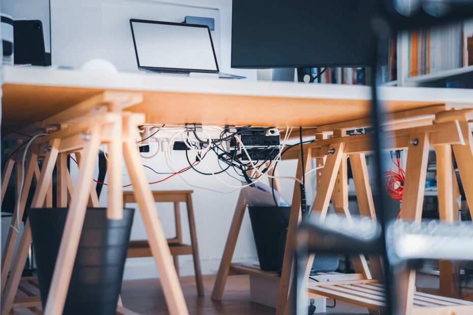 A stylish workspace with visible cables, laptop and monitor, highlighting modern technology's comple