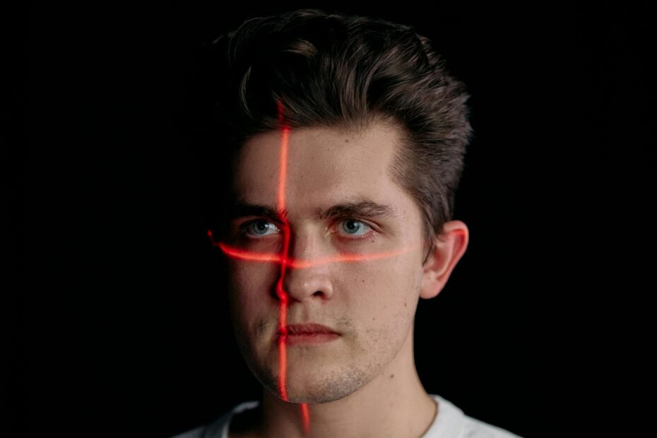 Conceptual portrait with laser scanning for facial recognition on plain black background.