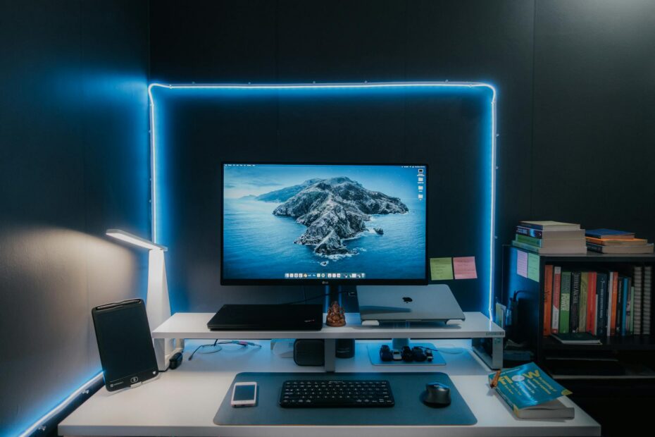 Stylish home office desk setup featuring LED lights, monitor, laptop, and essentials for a productiv