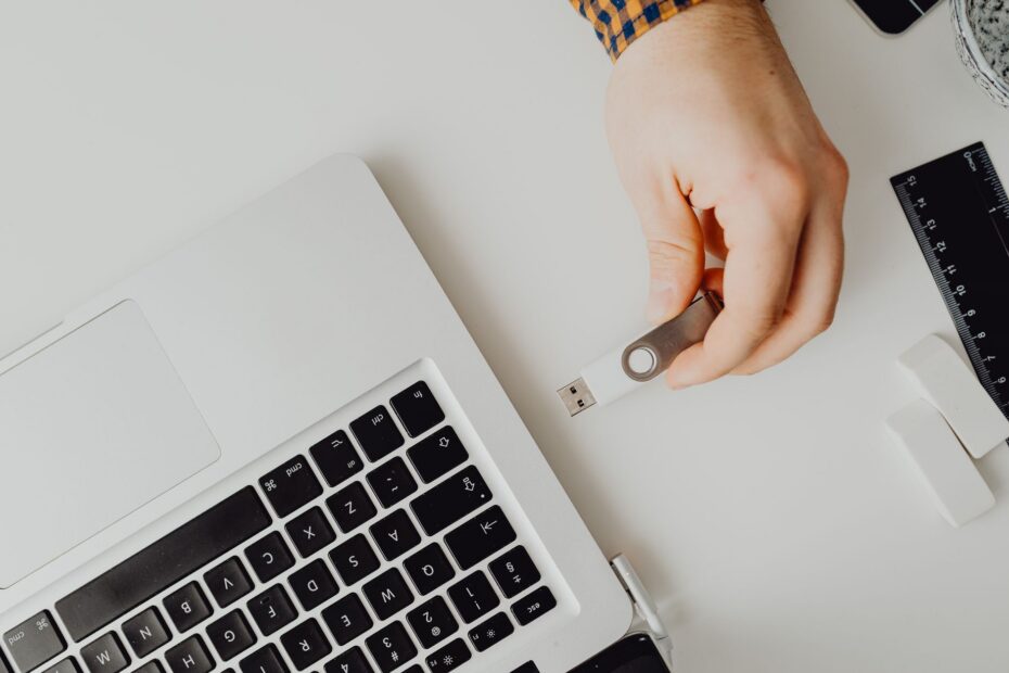 Hand inserting USB drive into laptop. Modern tech connection concept.