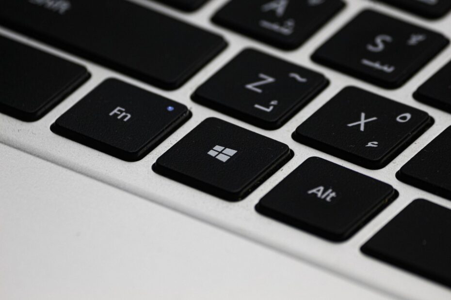 Detailed view of a laptop keyboard featuring Arabic letters and Windows key.