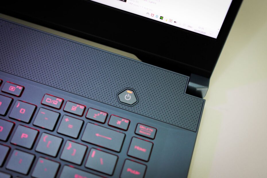 Detailed close-up image focusing on a modern laptop's power button and illuminated keyboard.