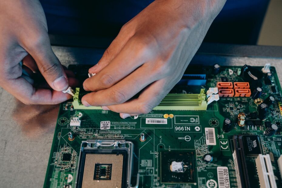 Hands carefully assembling a computer motherboard, showcasing technical craftsmanship in electronics